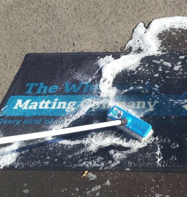 Washing a mat with soap and brush